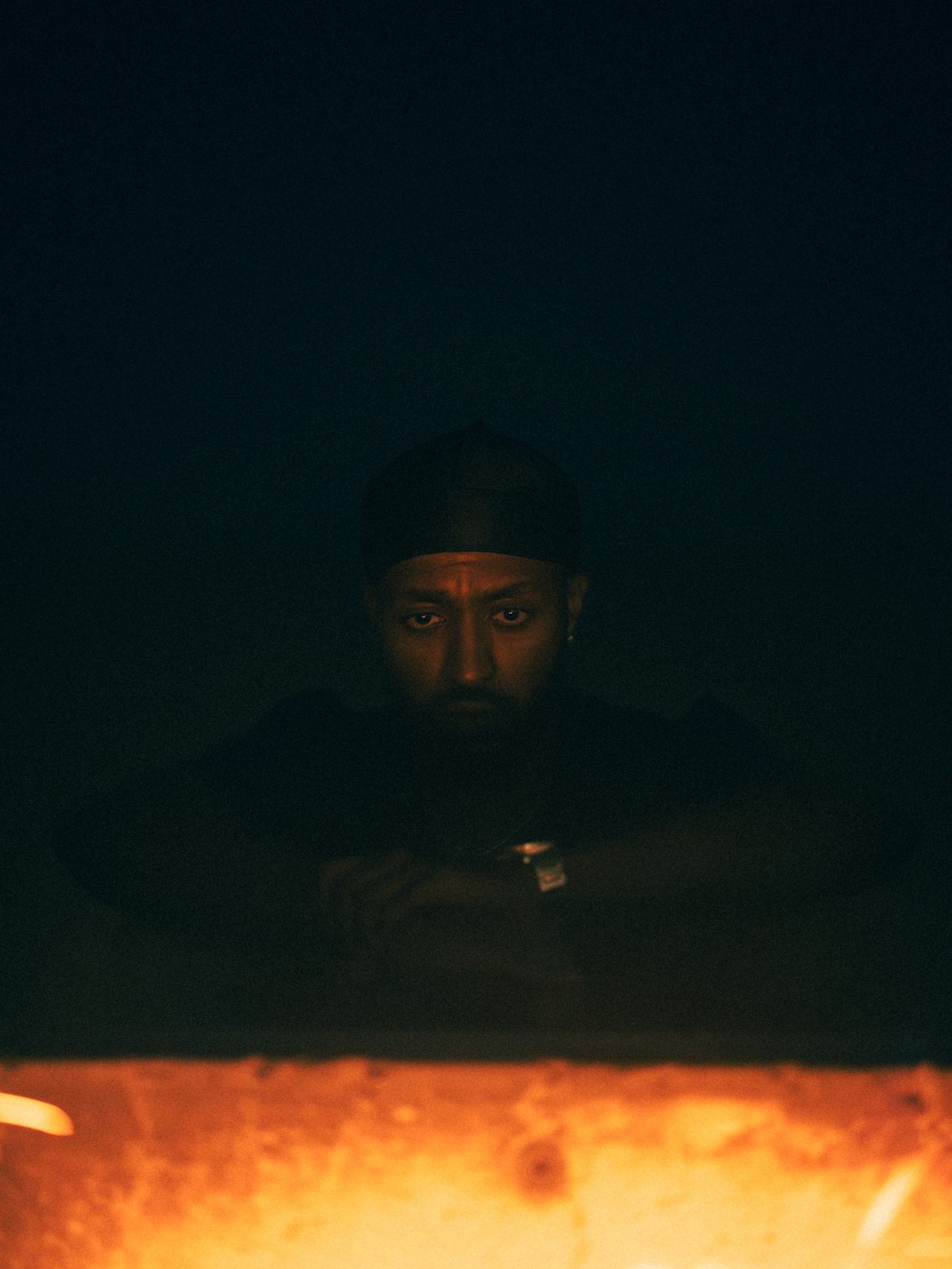 Menasseh lit by firelight, eyes to camera